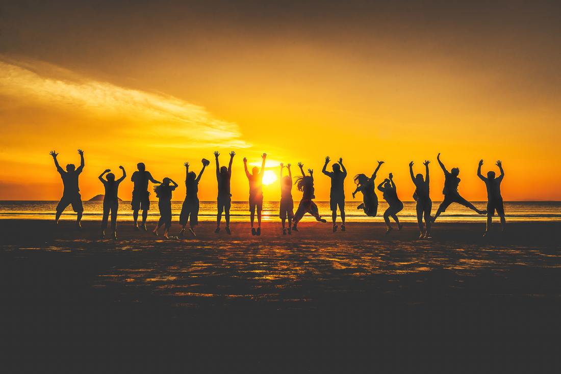 Silhouette group of people jumping on beach at sunset
